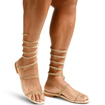 A woman wearing a beautiful pair of gold women's gladiator style sandals embellished with gold rhinestones covering the straps.
