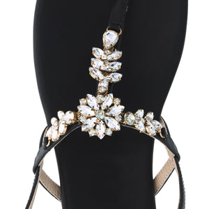 
                  
                    Load image into Gallery viewer, A top shot of a beautiful black women&amp;#39;s thong style sandal with a flat heel, sling back with buckle, and clear gemstones held with gold casing.
                  
                