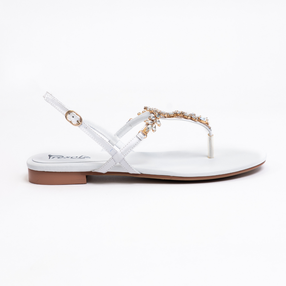 
                  
                    Load image into Gallery viewer, A side shot of a beautiful white women&amp;#39;s thong style sandal with a flat heel, sling back with buckle, and clear gemstones held with gold casing.
                  
                